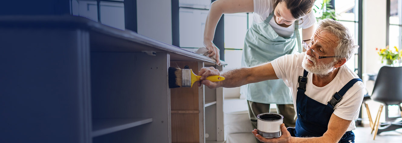 Couple painting piece of furniture together.