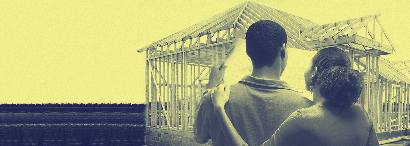 Couple looking at blueprints and framed home structure
