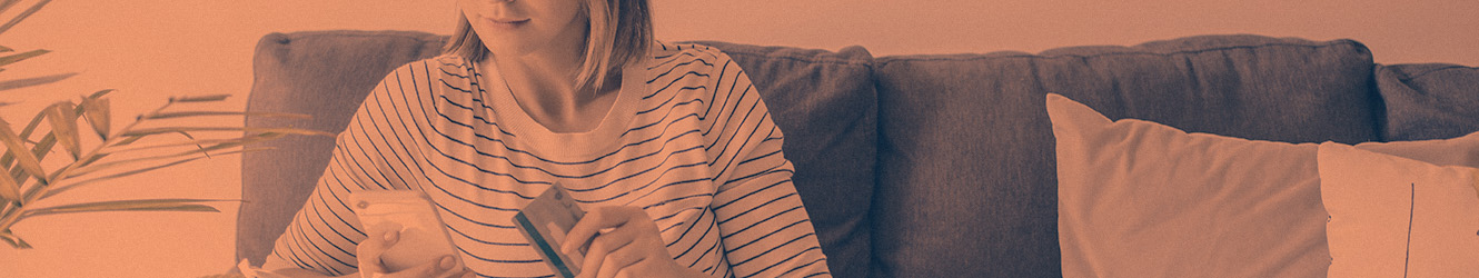 Woman on couch holding phone and credit card