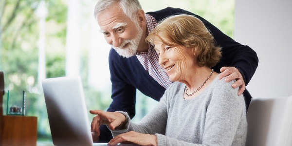elderly couple researching at laptop.